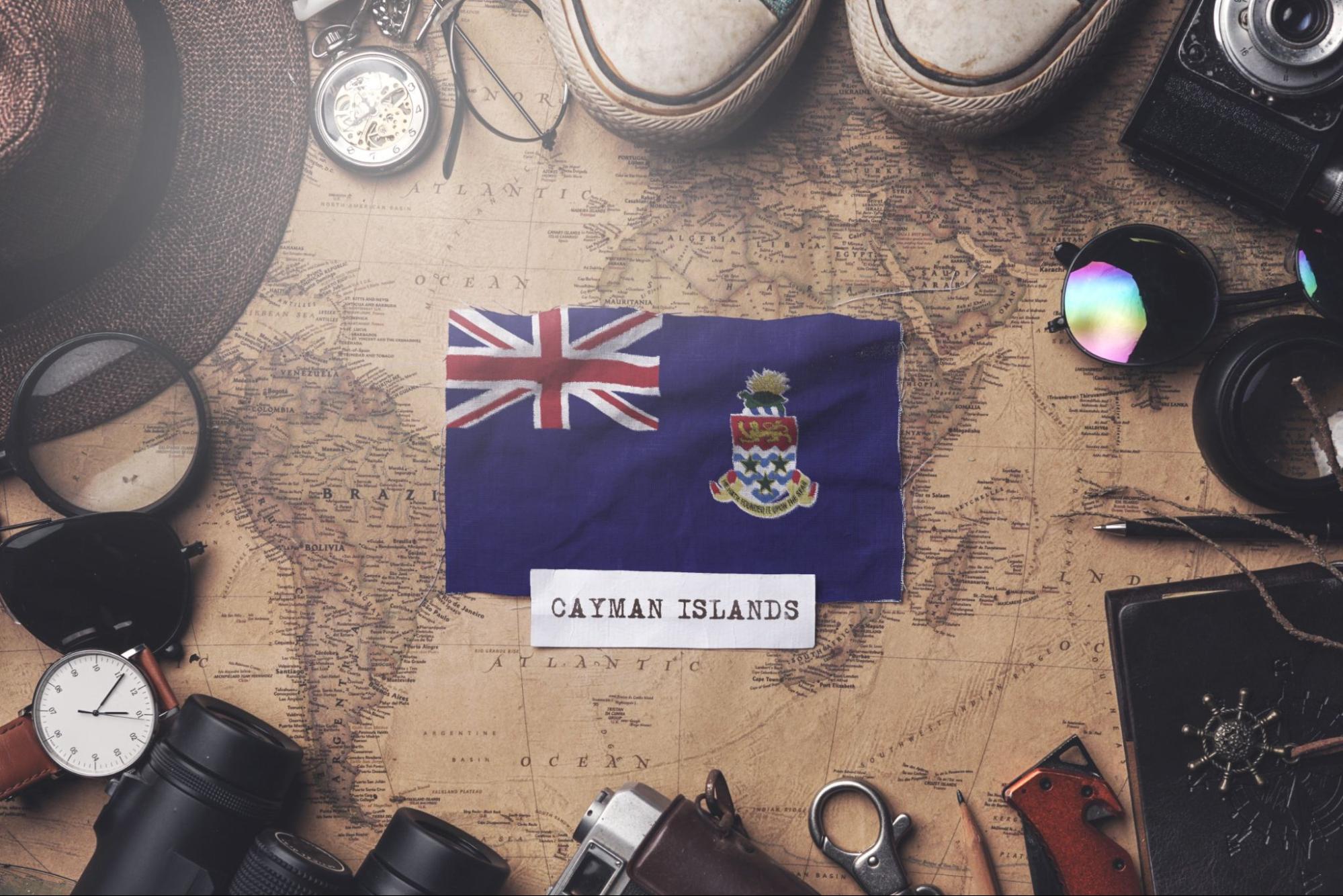Cayman Islands Flag Between Traveler's Accessories on Old Vintage Map