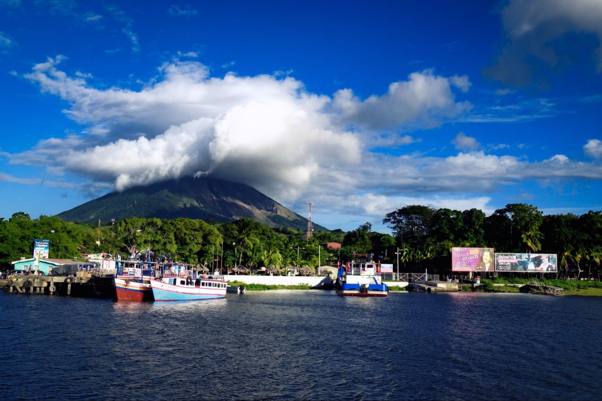 Moyogalpa port on Ometepe Island in Lake Nicaragua with fishing boats and cloud-topped Concepcion volcano in the background