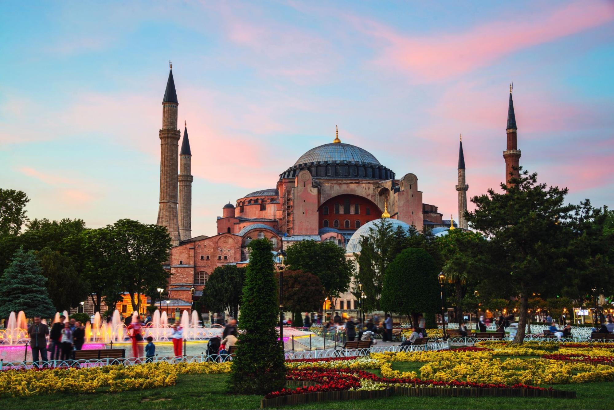 Hagia Sophia at sunset with motion blurred people walking by and illuminated fountain. Istanbul, Turkey
